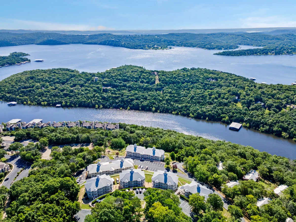 A serene view of a lake bordered by forested hills and residential buildings, offering a sense of peaceful seclusion while staying close to natural beauty. The image highlights the proximity to water and nature that guests can experience just outside the retreat.