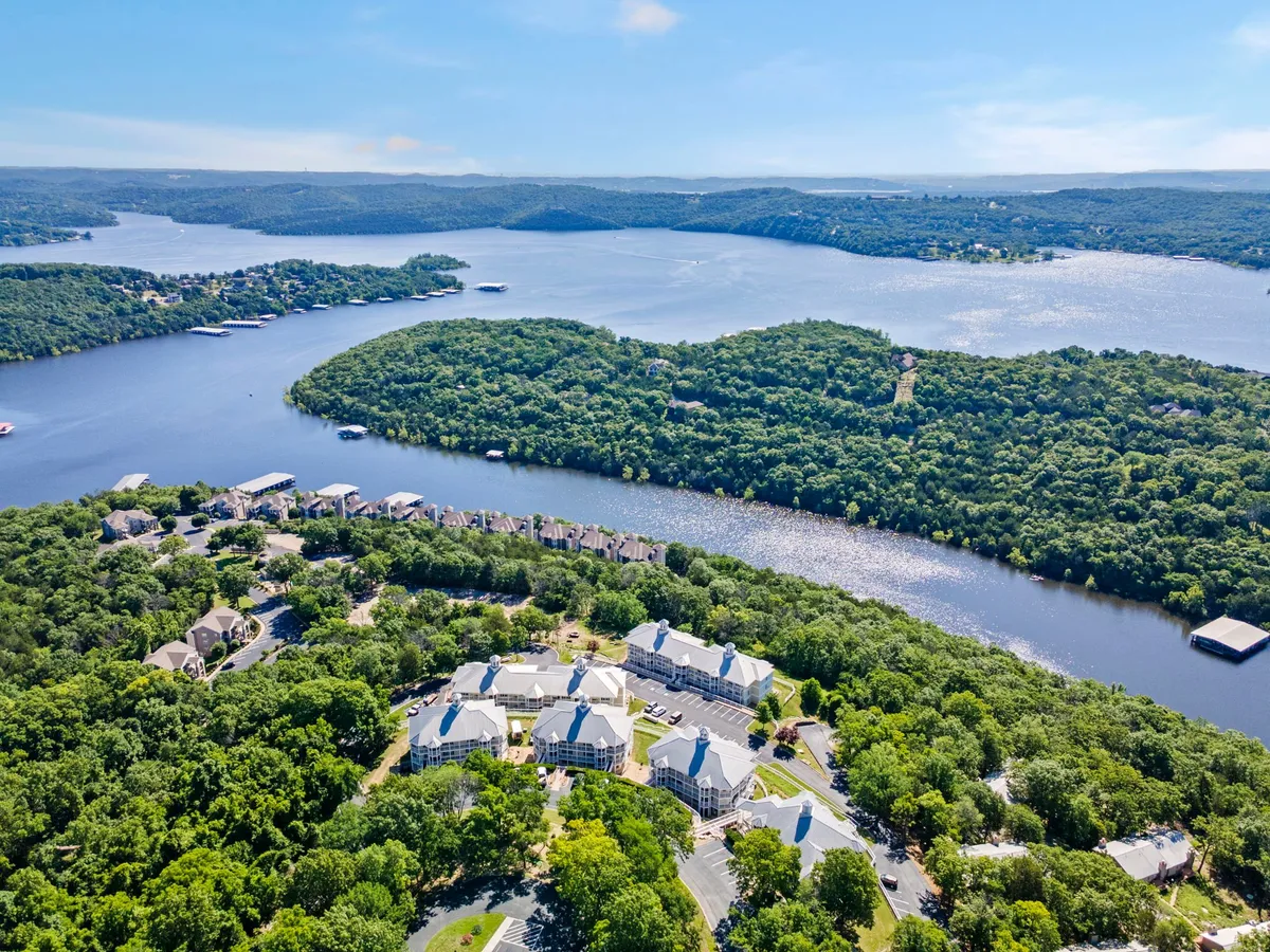 This view features a river winding past greenery and residential buildings, with open natural spaces and gentle hills. The expansive greenery and proximity to water highlight the area’s potential for outdoor adventures and tranquil exploration with pets.
