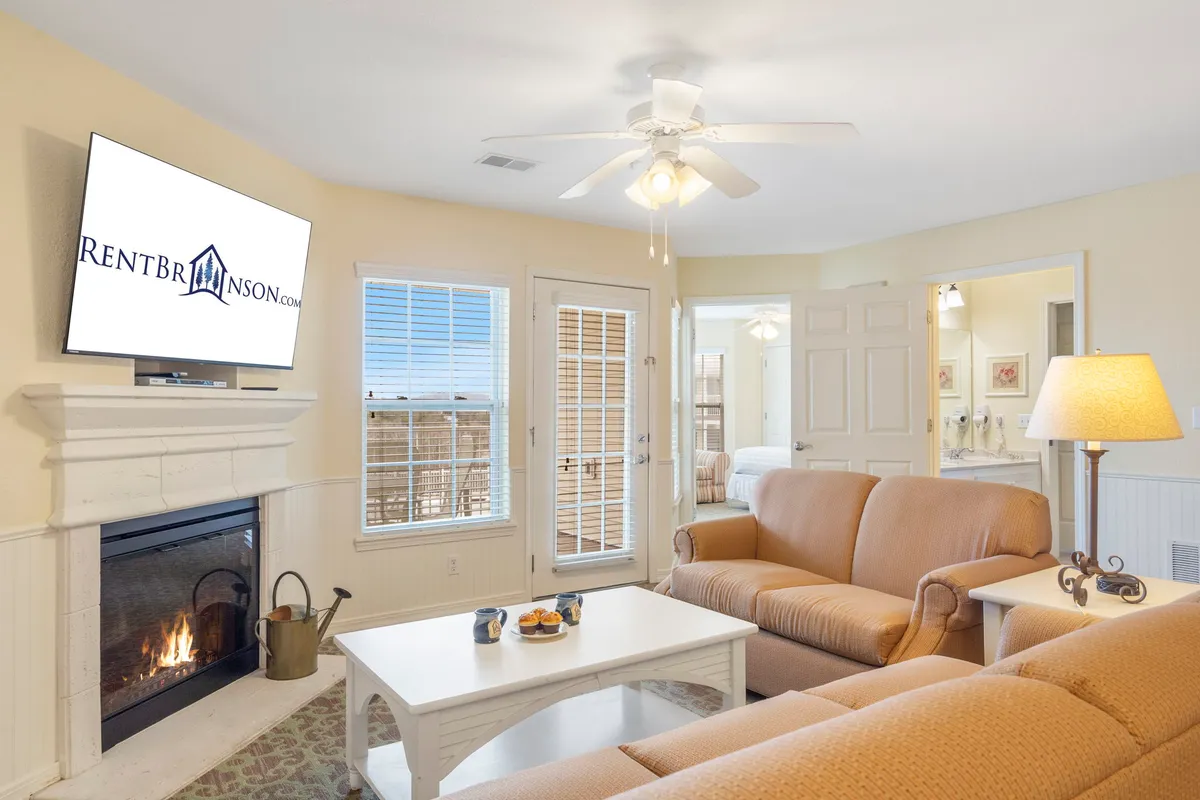 This interior image showcases a cozy living area with a plush sofa, a warm stone fireplace, a sleek television, and a spacious coffee table—creating a perfect setting for movie nights, relaxed conversations, or simply unwinding after a day at the lake.