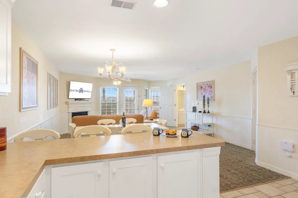 A wide-angle view of the open-concept interior encompassing the kitchen island, dining area, comfortable living area, and a television. The inviting layout flows together, encouraging family gatherings and relaxed evenings.